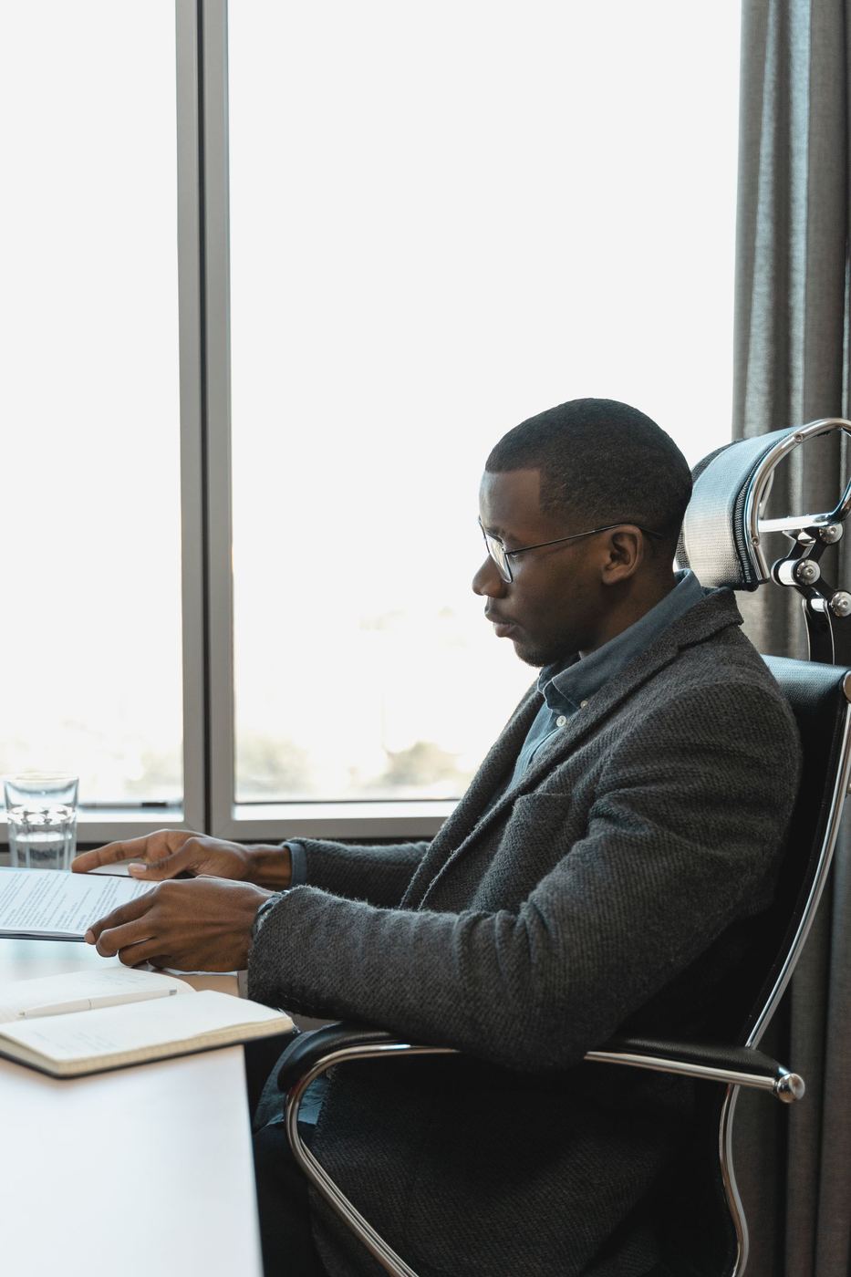Profissional sentado em cadeira ergonômica com apoio de cabeça, exemplo de postura adequada no posto de trabalho