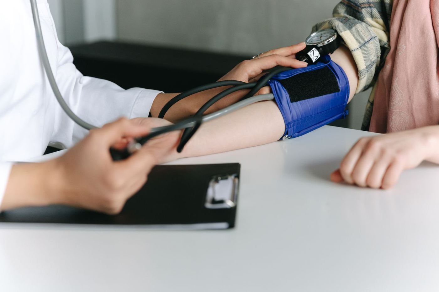 Médica aferindo a pressão arterial de um paciente durante consulta, representando os exames ocupacionais