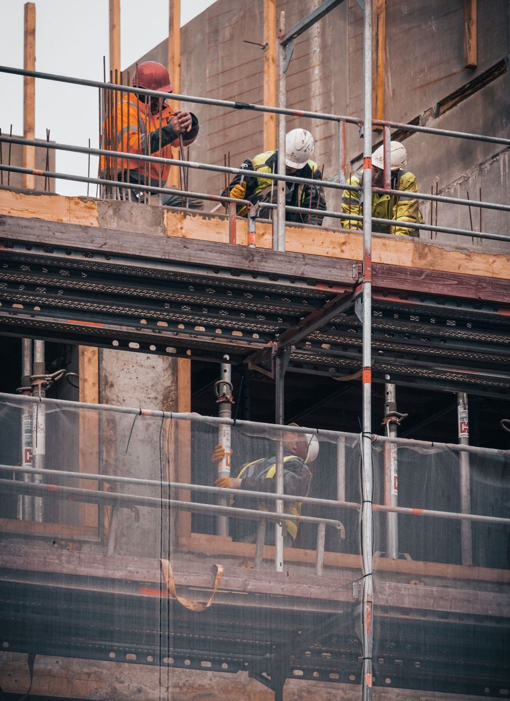 Trabalhadores da construção civil utilizando capacete e equipamentos de proteção individual em obra